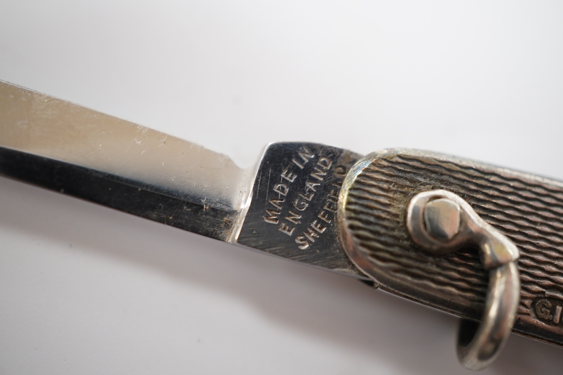 A George V engine turned silver and enamel pocket knife, decorated with R.M.S Queen Mary, the blades lifted by the handles, George Ibberson & Co, Sheffield, 1936, 76mm. Condition - poor to fair